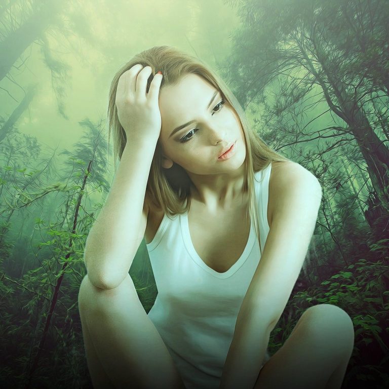 Junge Frau in einem Wald, nachdenklich sitzend, mit einem grünen Nebel im Hintergrund.