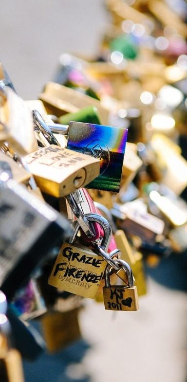 Bunte Liebesschlösser an einem Geländer, eng zusammengefasst.