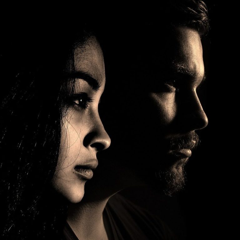 Woran erkennt man, ob eine Beziehung noch zu retten ist? Zwei Profile in Schwarz-Weiß, eine Frau links und ein Mann rechts, mit dramatischer Beleuchtung.